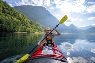 Kayak trip on the Geirangerfjord, Young man paddling in a kayak, atmospheric fjord landscape, Møre