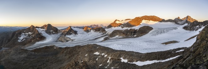 Picturesque high mountain landscape at sunrise with alpenglow, glacier and rocky mountain peaks in