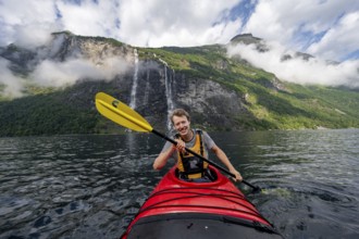 Kayak trip on the Geirangerfjord at the waterfall The Seven Sisters, Young man paddling in a kayak,