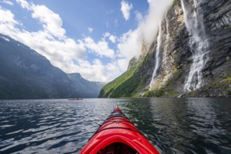 Kayak trip on the Geirangerfjord at the waterfall The Seven Sisters, tip of a red kayak in the