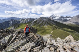 Mountaineer on the summit of Kastenegg, view of picturesque mountain landscape with snow-covered