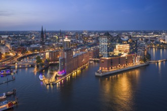 Aerial view of the Elbphilharmonie at blue hour with illuminated windows and view over the