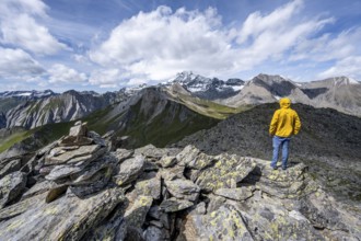 Mountaineer on the summit of Kastenegg, view of picturesque mountain landscape with snow-covered