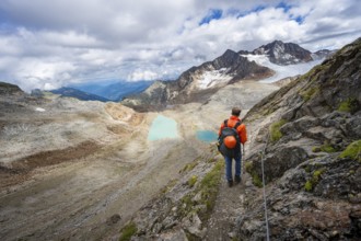 Mountaineer with helmet in high mountain landscape, view of blue glacial lakes, mountain peaks