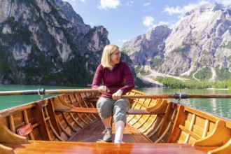 Smiling woman rowing in a boat on a mountain lake in sunny weather, Lake Braies, South Tyrol,
