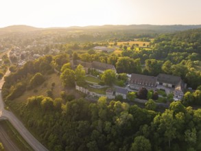 Wide aerial view of a monastery complex in a wooded landscape at sunset, event and wedding location