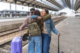 Students meeting at the train station are hugging each other after a long journey, happy to be