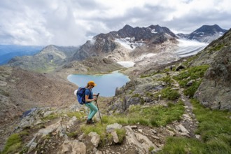 Mountaineer on hiking trail in dramatic high mountain landscape, view of mountains with mountain