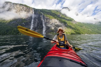 Kayak trip on the Geirangerfjord at the waterfall The Seven Sisters, Young man paddling in a kayak,