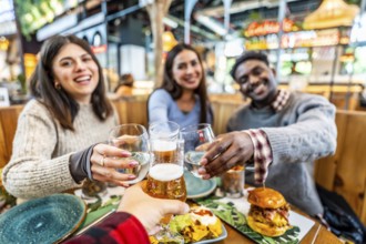 Happy friends enjoying a meal together, raising their glasses in a cheerful toast at a vibrant