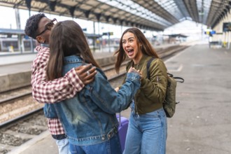 Three cheerful multi ethnic friends greeting each other on a train station platform, excited for