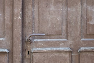Weathered brown wooden door with rusty door handle and visible texture, Bad Bergzabern, Southern