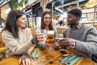 Multi ethnic friends smiling and toasting with beer and water at a brewery pub, enjoying their time