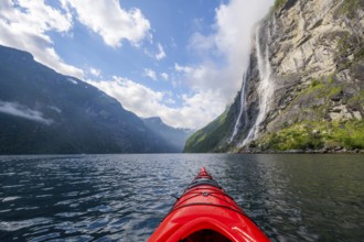 Kayak trip on the Geirangerfjord at the waterfall The Seven Sisters, tip of a red kayak in the