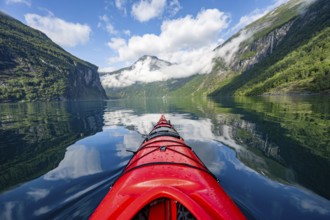 Kayak trip on the Geirangerfjord, tip of a red kayak in the fjord with reflection, atmospheric