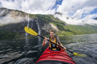 Kayak trip on the Geirangerfjord at the waterfall The Seven Sisters, Young man paddling in a kayak,