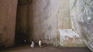 Cave Ear of Dionysus, Large rock cave with several people exploring the dark surroundings, Neapolis