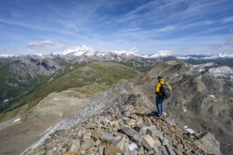 Mountaineer at the summit of Böses Weibl, view of picturesque mountain landscape with snow-covered