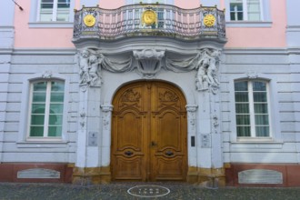 Magnificent wooden door of a pink façade with classical sculptures and decorative details in