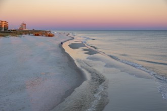 Woman and child walking along the Gulf of Mexico beach as the sun rises over the Gulf of Mexico at