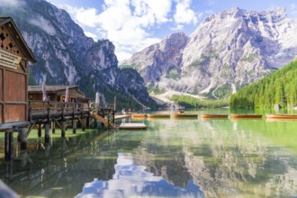 Wooden huts on the lakeshore against a majestic mountain backdrop and calm waters, Lake Braies,