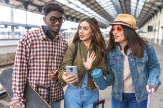 Group of young tourists chatting on a smartphone while walking through a bustling train station,