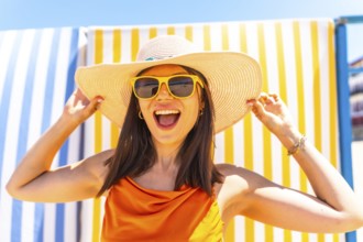 Young woman wearing a straw hat and sunglasses, smiling brightly while enjoying the summer sun,