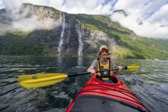 Kayak trip on the Geirangerfjord at the waterfall The Seven Sisters, Young man paddling in a kayak,