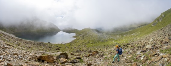 Mountaineer on a hiking trail, cloudy mountain landscape with mountain lake, Middle Moarer Egetsee,
