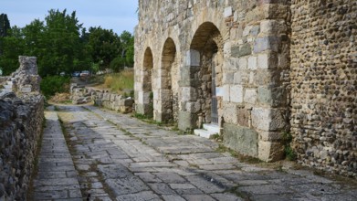 Historic stone street next to an ancient wall with arches, Basilica, Street, Archaeological site,