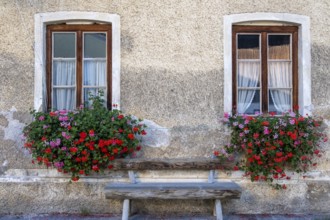 Two windows with flower boxes and wooden bench on a charming stone wall, Umrathshausen, Bavaria,
