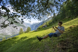 Young man swinging, Blomberg Gård, historic mountain farm with grass roof on a steep mountainside