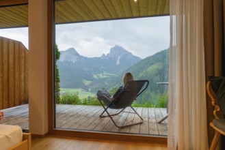 Cosy view from a window to the mountains, person sitting relaxed in an armchair, Dolomites, South