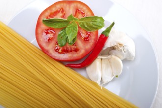 Italian spaghetti pasta tomato raw ingredients basil garlic and red chili pepper