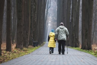 Grandfather and granddaughter walking together in the park