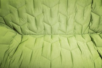 Close-up comfortable green soft sofa with curly stitching. Modern design