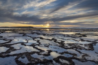 A beautiful sunset over the ocean with rocky beach and tidal pools in the foreground