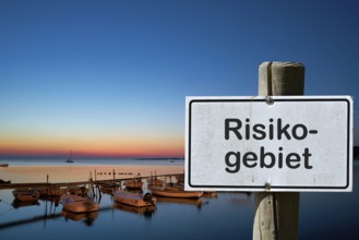 Sign with the inscription risk area. Due to many new corona infections, areas are designated as