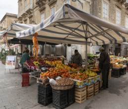 Syracuse, Italy, 28 December, 2023: greengrocer selling fruit and vegetables to customers in the