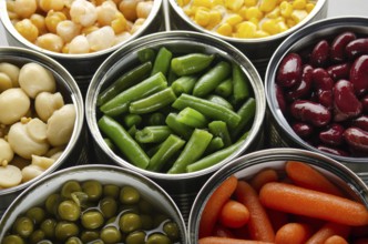 Canned vegetables in opened tin cans on kitchen table. Non-perishable long shelf life foods