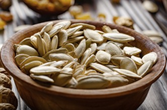 Pumpkin seeds in wooden bowl on kitchen table food background