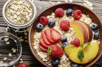 Flat lay of fruit healthy muesli with peaches strawberry almonds and blackberry in clay dish on