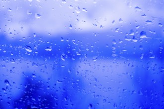 Raindrops on a window, illustrating gray and rainy weather during the day. Black and white