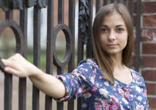 Portrait of a beautiful girl near the old rusty wrought fence