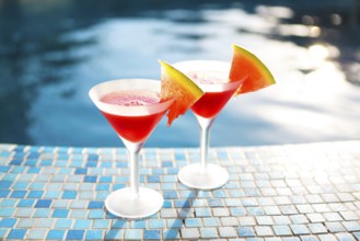Glasses of watermelon cocktail with watermelon slices near the pool