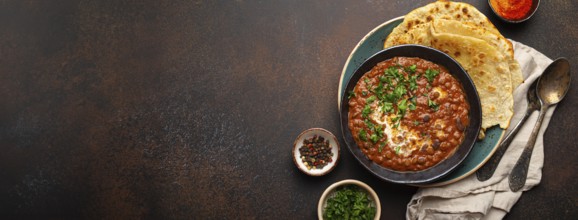 Traditional Indian Punjabi dish Dal makhani with lentils and beans in black bowl served with naan