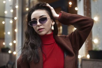 Portrait of a Woman in sunglasses fixing her hair on the street