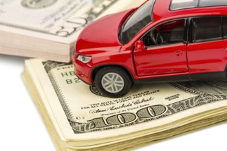 A car is written on dollar notes. Costs for car purchase, petrol, insurance and other car costs