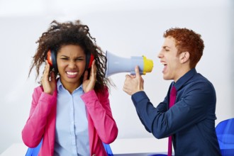 Businessman shouting in megaphone to african executive with scared expression