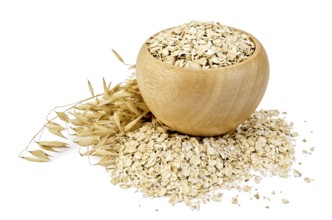 Oat flakes in a wooden bowl, oat stalks, oat flakes scattered on the table, against a white
